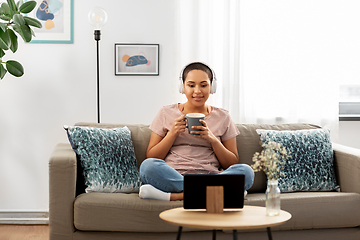 Image showing woman with headphones and tablet pc drinking tea