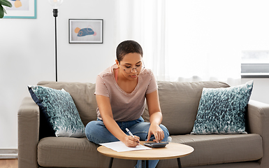 Image showing african woman with papers and calculator at home