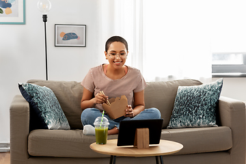 Image showing african woman with tablet pc eating takeaway food