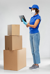 Image showing delivery woman in mask with boxes and tablet pc