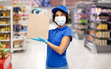 Image showing delivery woman in mask with food in bag at store