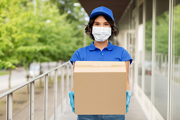 Image showing delivery woman in mask holding parcel box outdoors