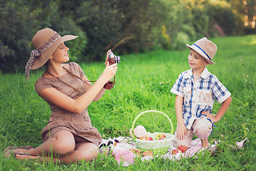 Image showing Little boy and teen age girl having picnic outdoors