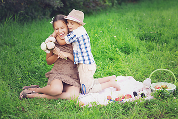 Image showing Little boy and teen age girl having picnic outdoors