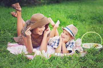 Image showing Little boy and teen age girl having picnic outdoors