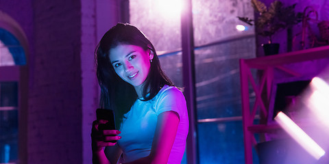 Image showing Cinematic portrait of handsome young woman in neon lighted interior