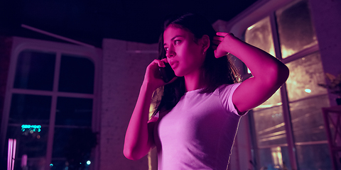 Image showing Cinematic portrait of handsome young woman in neon lighted interior