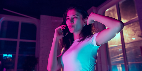 Image showing Cinematic portrait of handsome young woman in neon lighted interior