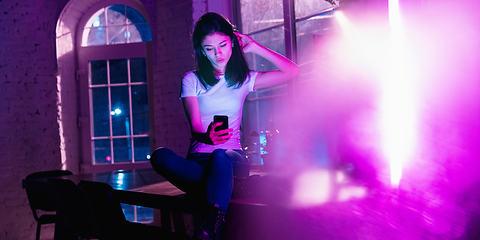 Image showing Cinematic portrait of handsome young woman in neon lighted interior