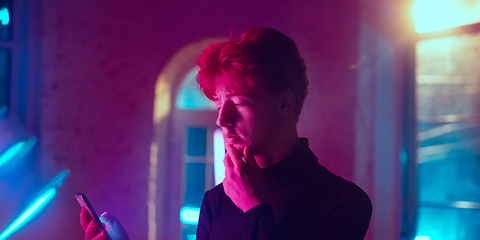 Image showing Cinematic portrait of handsome young man in neon lighted interior