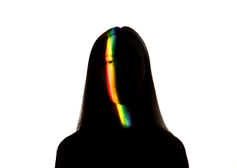 Image showing Dramatic portrait of a girl in the dark on white studio background with rainbow colored line