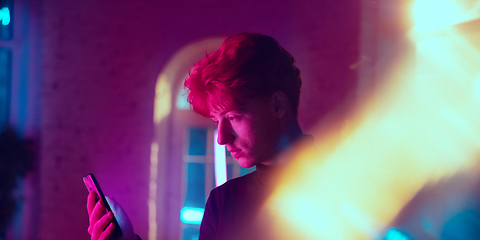 Image showing Cinematic portrait of handsome young man in neon lighted interior