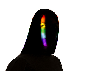 Image showing Dramatic portrait of a girl in the dark on white studio background with rainbow colored line