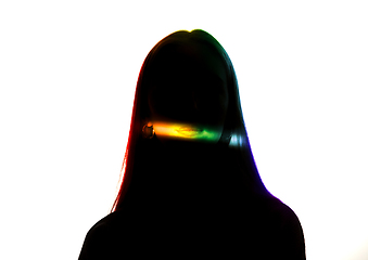 Image showing Dramatic portrait of a girl in the dark on white studio background with rainbow colored line