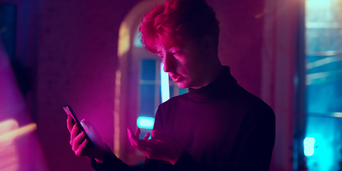 Image showing Cinematic portrait of handsome young man in neon lighted interior