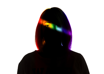 Image showing Dramatic portrait of a girl in the dark on white studio background with rainbow colored line