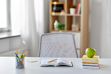 Image showing books, apple and school supplies on table at home