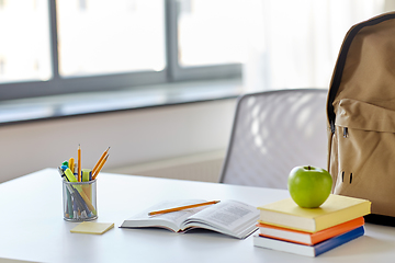 Image showing books, apple and school supplies on table at home