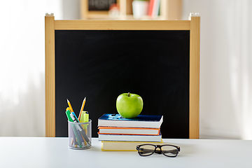 Image showing books, apple and school supplies on table at home