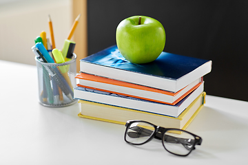 Image showing books, apple and school supplies on table at home