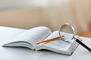 Image showing book with magnifier and pencil on table at home