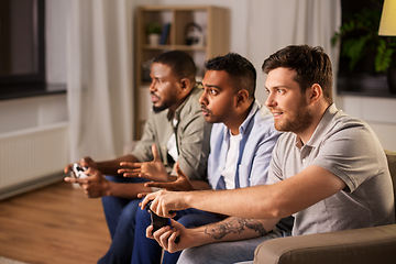 Image showing happy friends playing video games at home at night