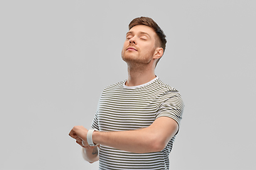 Image showing calm young man with smart watch meditating