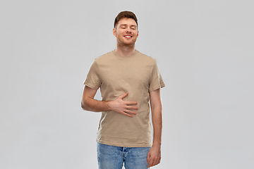 Image showing happy full man touching tummy over gray background