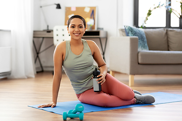 Image showing smiling woman with bottle and dumbbells at home