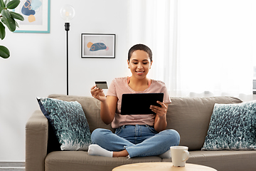 Image showing happy woman with tablet pc and credit card at home