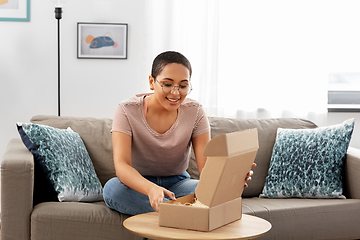 Image showing african american woman opening parcel box at home