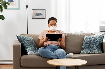 Image showing woman in medical mask with tablet pc at home