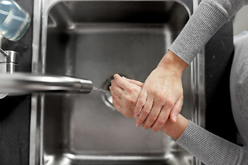 Image showing woman washing hands with liquid soap in kitchen