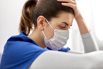 Image showing sad doctor or nurse in face mask holding to head