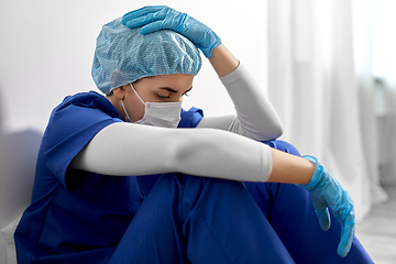 Image showing sad doctor or nurse in face mask holding to head