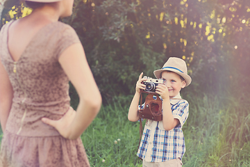 Image showing handsome little boy with retro camera and girl model