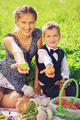 Image showing Little boy and teen age girl having picnic outdoors