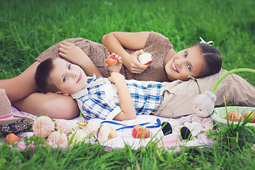 Image showing Little boy and teen age girl having picnic outdoors