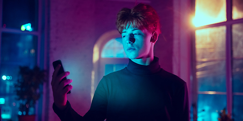 Image showing Cinematic portrait of handsome young man in neon lighted interior