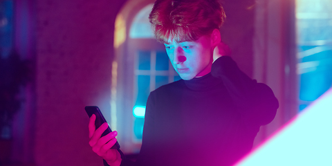 Image showing Cinematic portrait of handsome young man in neon lighted interior