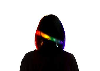 Image showing Dramatic portrait of a girl in the dark on white studio background with rainbow colored line