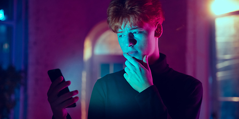 Image showing Cinematic portrait of handsome young man in neon lighted interior