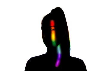 Image showing Dramatic portrait of a girl in the dark on white studio background with rainbow colored line