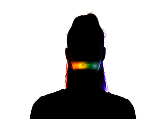 Image showing Dramatic portrait of a girl in the dark on white studio background with rainbow colored line