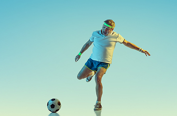 Image showing Senior man playing football in sportwear on gradient background and neon light