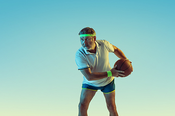 Image showing Senior man playing basketball in sportwear on gradient background and neon light