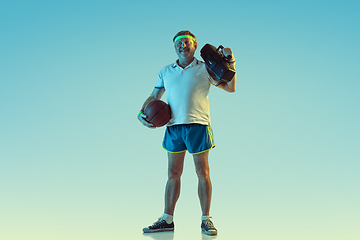 Image showing Senior man posing stunning in sportwear with retro tape recorder on gradient background and neon light