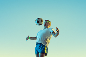 Image showing Senior man playing football in sportwear on gradient background and neon light