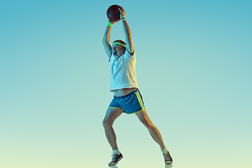 Image showing Senior man playing basketball in sportwear on gradient background and neon light
