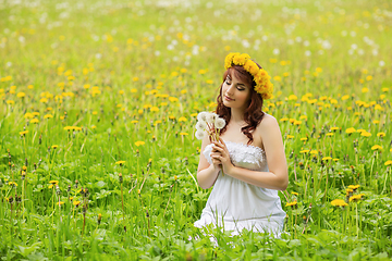 Image showing beautiful girl with dandelion flowers in green field